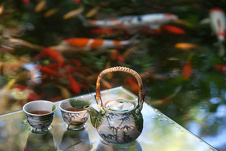 大尾锦鲤鱼夏日池塘边的茶具背景
