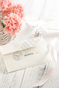 粉色康乃馨花束桌上的康乃馨花和信封贺卡背景