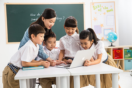 教室里的小学生现代户内小学女生教师和小学生在教室里使用电脑背景