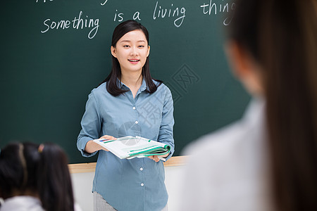 微笑的关爱青年女人老师和小学生们在教室里图片