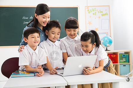 教育业职位10岁到11岁关爱教师和小学生在教室里使用电脑图片