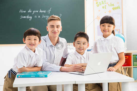 相伴电脑户内教师和小学生在教室里图片