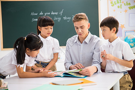 相伴小学女生好奇心教师和小学生在教室里图片