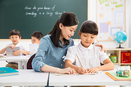 孩子在黑板写字桌子无忧无虑团结老师和小学生们在教室里背景