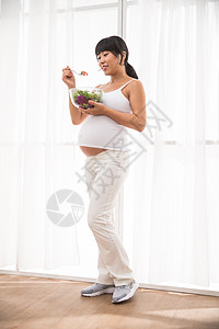 20多岁舒适健康的幸福的孕妇吃蔬菜沙拉背景