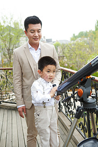 探索父亲和儿子在阳台使用天文望远镜图片