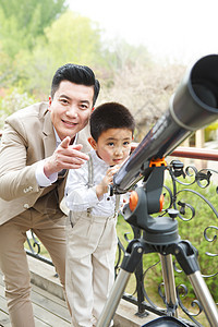 童年父亲和儿子在阳台使用天文望远镜图片