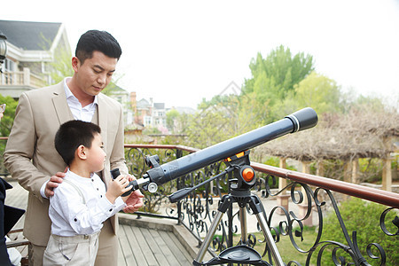 家庭生活父亲和儿子在阳台使用天文望远镜图片
