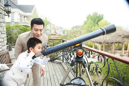 幸福父亲和儿子在阳台使用天文望远镜图片