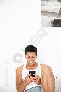 帅哥休闲20多岁青年男人在卧室玩手机图片