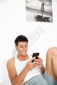 白昼住宅内部青年男人在卧室玩手机图片