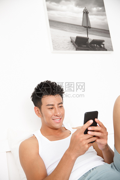 白昼休闲追求青年男人在卧室玩手机图片