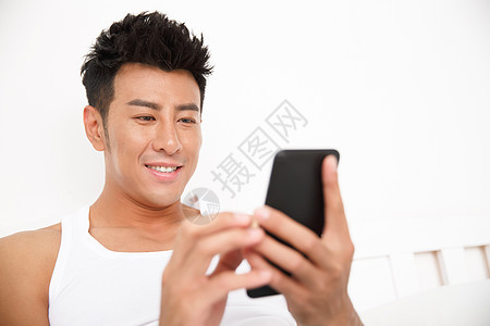 幸福舒适网上冲浪青年男人在卧室玩手机图片