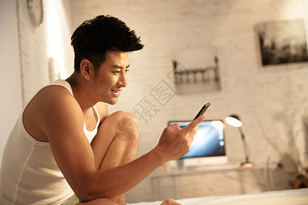 青年人亚洲无忧无虑青年男人在卧室玩手机图片