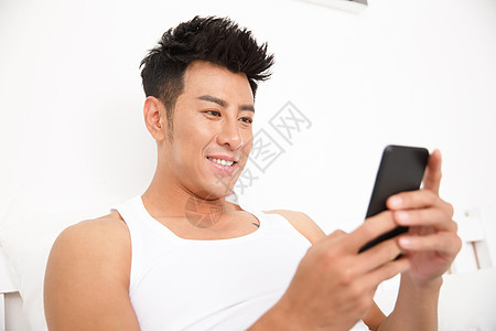 白昼宅男无忧无虑青年男人在卧室玩手机图片