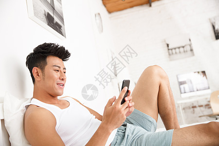 东方人宅男家庭生活青年男人在卧室玩手机图片