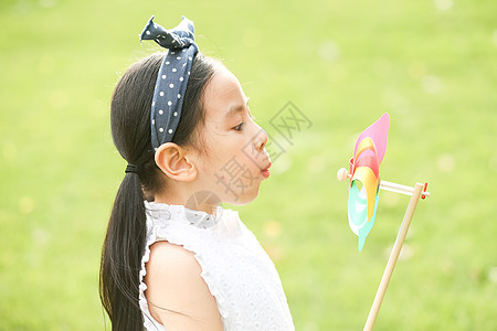 小女孩在户外玩耍吹风车图片