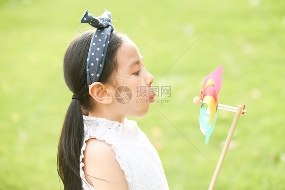 小女孩在户外玩耍吹风车图片