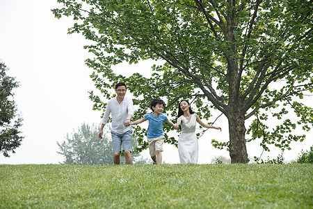 成年人健康生活方式关爱一家三口在草地上奔跑图片