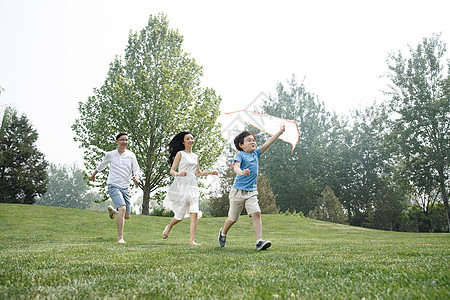 休闲活动一家三口在草地上奔跑图片