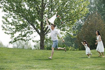 5到6岁健康生活方式女孩一家三口在草地上放风筝图片
