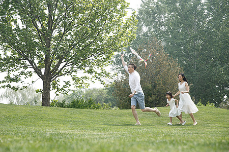 女儿青年男人青年伴侣一家三口在草地上放风筝图片