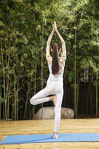 青年人高举手臂单腿站着青年女人练习瑜伽图片