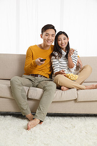 人和谐25岁到29岁青年情侣坐着沙发上看电视图片
