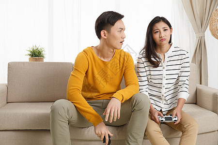 青年夫妇彩色图片水平构图青年情侣坐着沙发上玩游戏图片