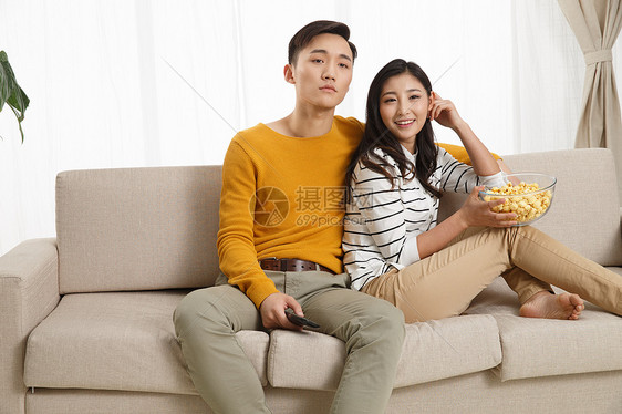 高兴的异恋亚洲青年情侣坐着沙发上看电视图片