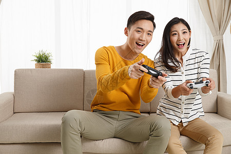 20到24岁异恋幸福青年情侣坐着沙发上玩游戏图片