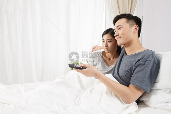 20到24岁女朋友青年夫妇青年情侣坐着床上看电视图片