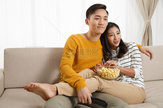 彩色图片微笑摄影青年情侣坐着沙发上看电视图片