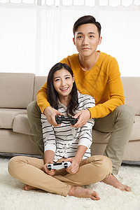 亚洲异恋快乐青年情侣坐着沙发上玩游戏图片