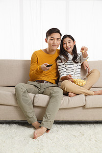住宅房间垂直构图表情青年情侣坐着沙发上看电视图片