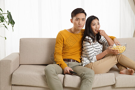 亚洲快乐幸福青年情侣坐着沙发上看电视图片