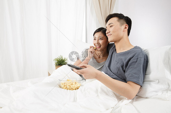人水平构图青年人青年情侣坐着床上看电视图片