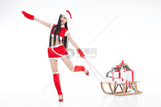 雪橇消费拉着圣诞礼物的年轻女人图片