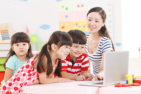 娱乐室坐着快乐幼儿园里老师和儿童使用电脑图片