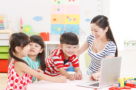 坐着互联网知识幼儿园里老师和儿童使用电脑图片