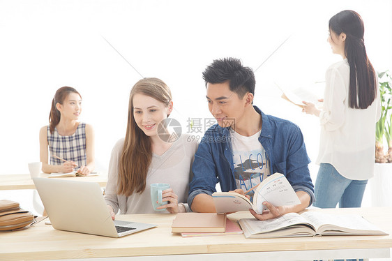 坐着西方人同学年轻的大学生在学习图片