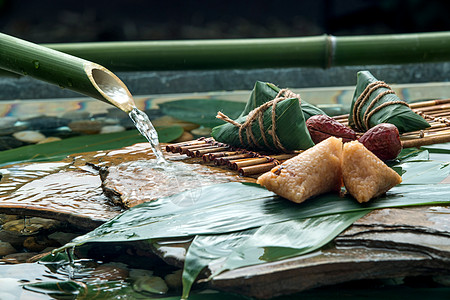 流水旁粽叶上的肉粽背景图片