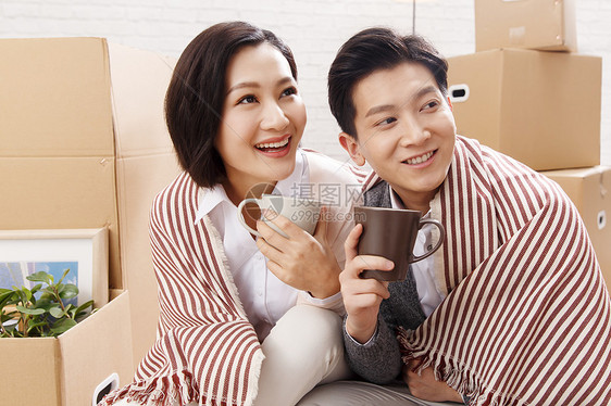 纸箱住宅内部幸福年轻夫妇坐在地板上喝水图片
