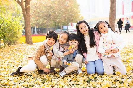 跪着树东方人可爱的男孩女孩在户外玩耍图片