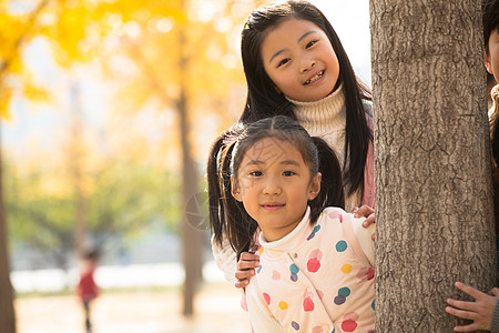 站在树上女孩小学生朋友树林两个可爱的小女孩在户外玩耍背景