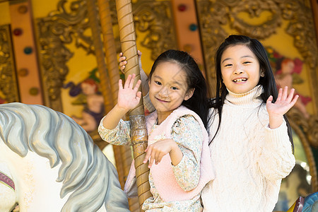 东方人朋友娱乐两个小女孩在玩旋转木马图片