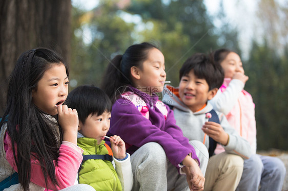 秋天朋友棒棒糖可爱的男孩女孩在户外玩耍图片