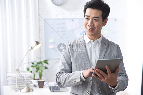 轻松办公室公司企业青年商务男人拿着平板电脑办公图片