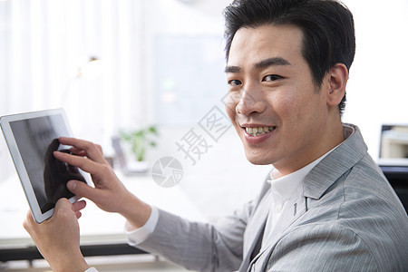 东方人新创企业满意青年商务男人拿着平板电脑办公图片