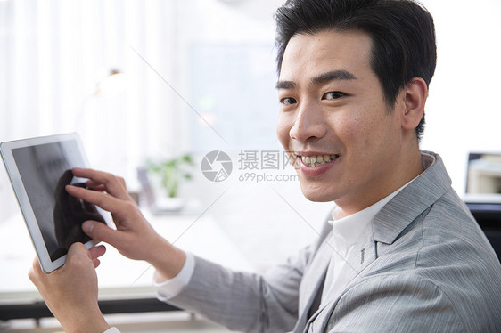 东方人新创企业满意青年商务男人拿着平板电脑办公图片
